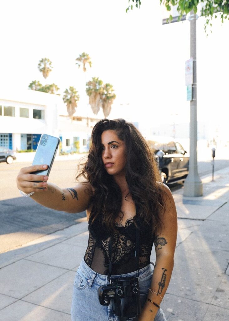 woman in black and white floral sleeveless top holding blue smartphone
